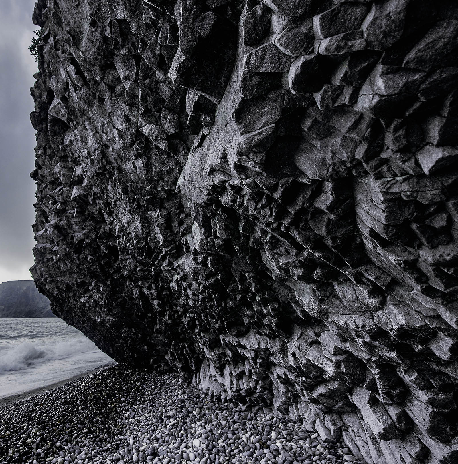 Scenic graphite rock at the seashore in cloudy weather