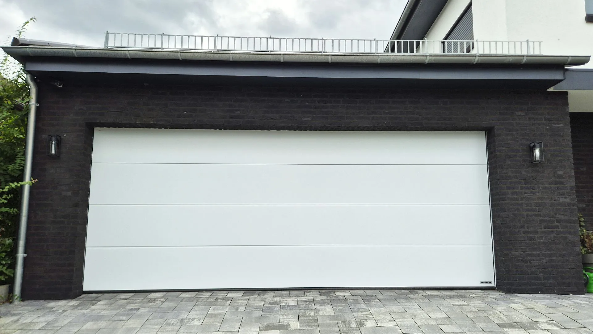 Garage mit schwarzem Klinker und weißem Garagentor