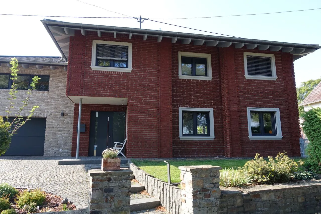 Klassisch rotes Klinkerhaus mit Anbau. Die rotgeflammten Backsteinriemchen kommen mit den weißen Fenstern gut zur Geltung. Der Anbau wurde mit der Sorte Antik vintage verarbeitet, ein grau gehaltenes Riemchen.