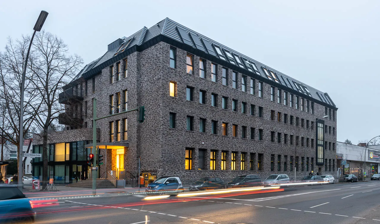 Großflächige, dunkle Fassade eines Bürogebäudes. Die Sorte Retro Shadow aus schwarzen und grauen Steinen ist zeitlos und klassisch. Mit dunklen Fensterrahmen und Akzenten wirkt das Gebäude edel. Tolle Akzente durch Beleuchtung.