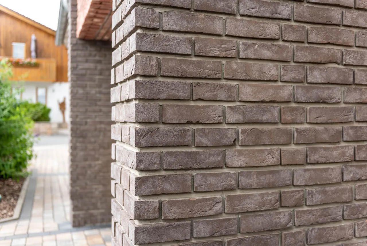Garage mit der Sorte Lava. Die grauen Klinkerriemchen und Winkelriemchen sehen modern und besonders aus. Durch den Schmolz lockert das Gesamtbild auf