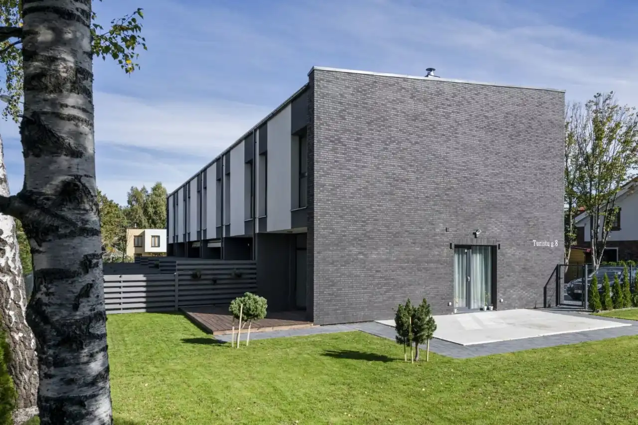 Titan Petino an einer Hausfasade mit Garten im Vordergrund