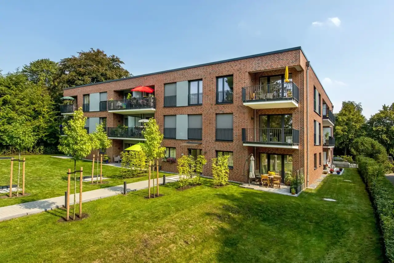 Gartenansicht eines Mehrfamilienhauses mit der Sorte Titan Carbo in rot