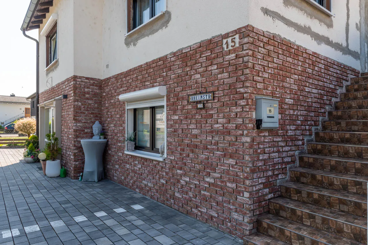 Hier wurde der untere Teil einer Hausfassade mit den Klinkerriemchen der Sorte Antik rustik verklinkert. die rot-bunten Ziegelriemchen geben hier einen schönen Kotrast zum restlichen Haus