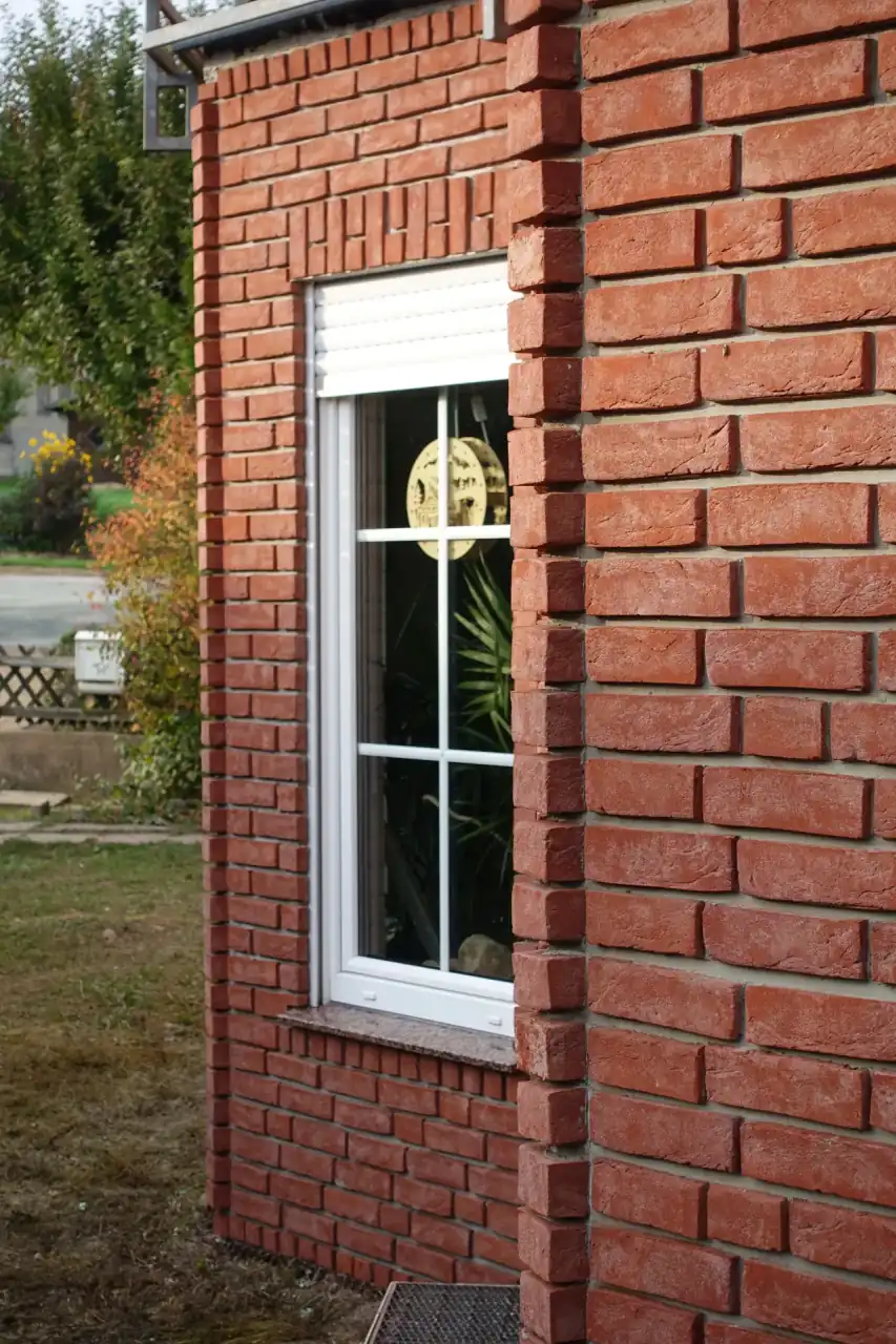 Detailaufnahme eines Erkers mit weißen Fenstern und roter Fassade