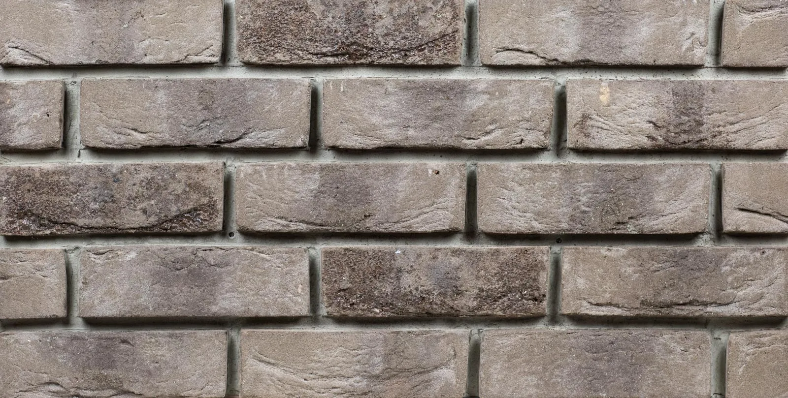 Produktbild frontal Klinkerriemchen Lava. Ein graues Riemchen mit Schmolz. Quasi Geschmolzener Stein zum ANfassen. Die Oberfläche ist genarbt und fein hell besandet