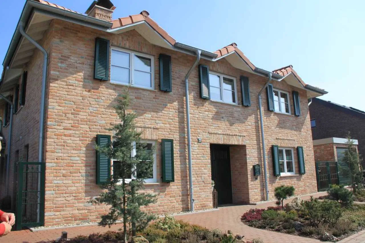 Haus mit Backsteinriemchen Mediterran Finca und gruenen Klapplaeden