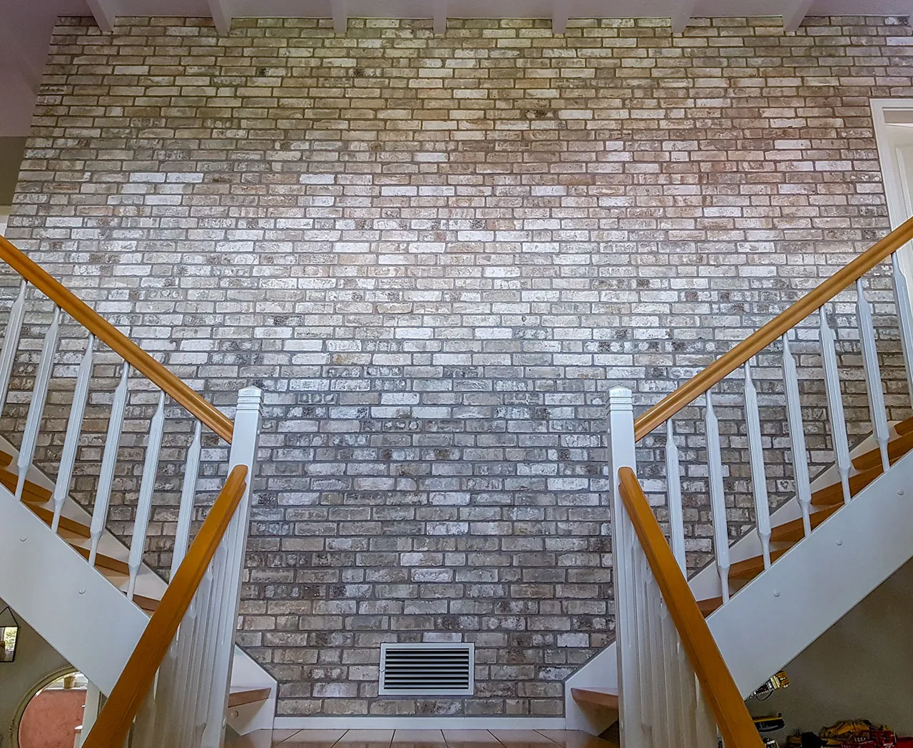 Klinkerriemchen Irish moor Ziegelwand im Treppenhaus. Die gelben, leicht bronzefarbene Klinkerriemchen der Sorte Irish Moor ist mit einer leichten weißen Schlemme verziert. Die Ziegelwand sieht hell und freundlich im lichtdurchfluteten Raum aus.