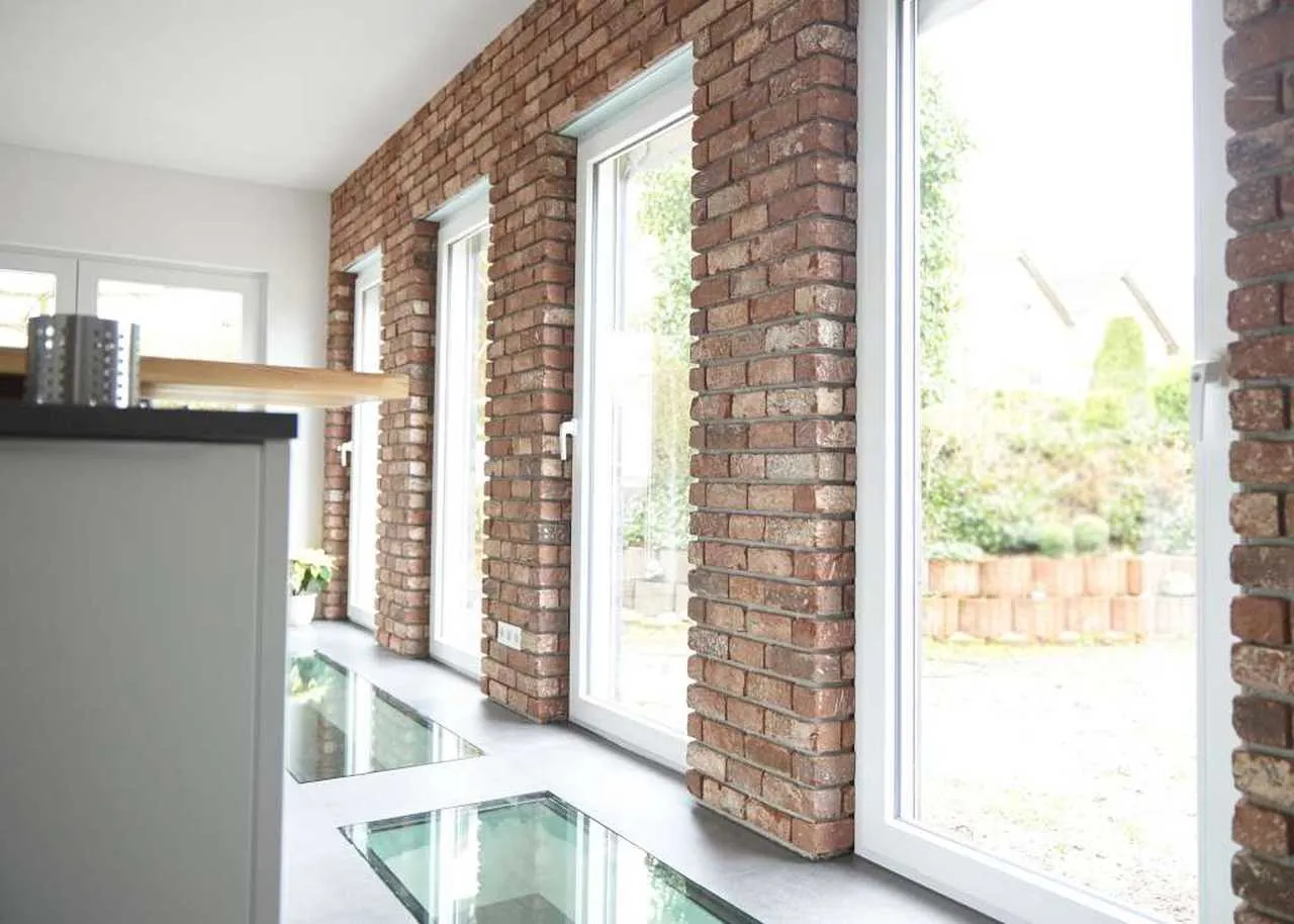 Klinkerriemchenwand im Küchenbereich. Die Wand in edlem Rot mit gelb, schwarzerm Brand umrandet die Bodenlangen Balkontüren. Ein heller Raum, der die Wand hervorhebt. Edel, modern