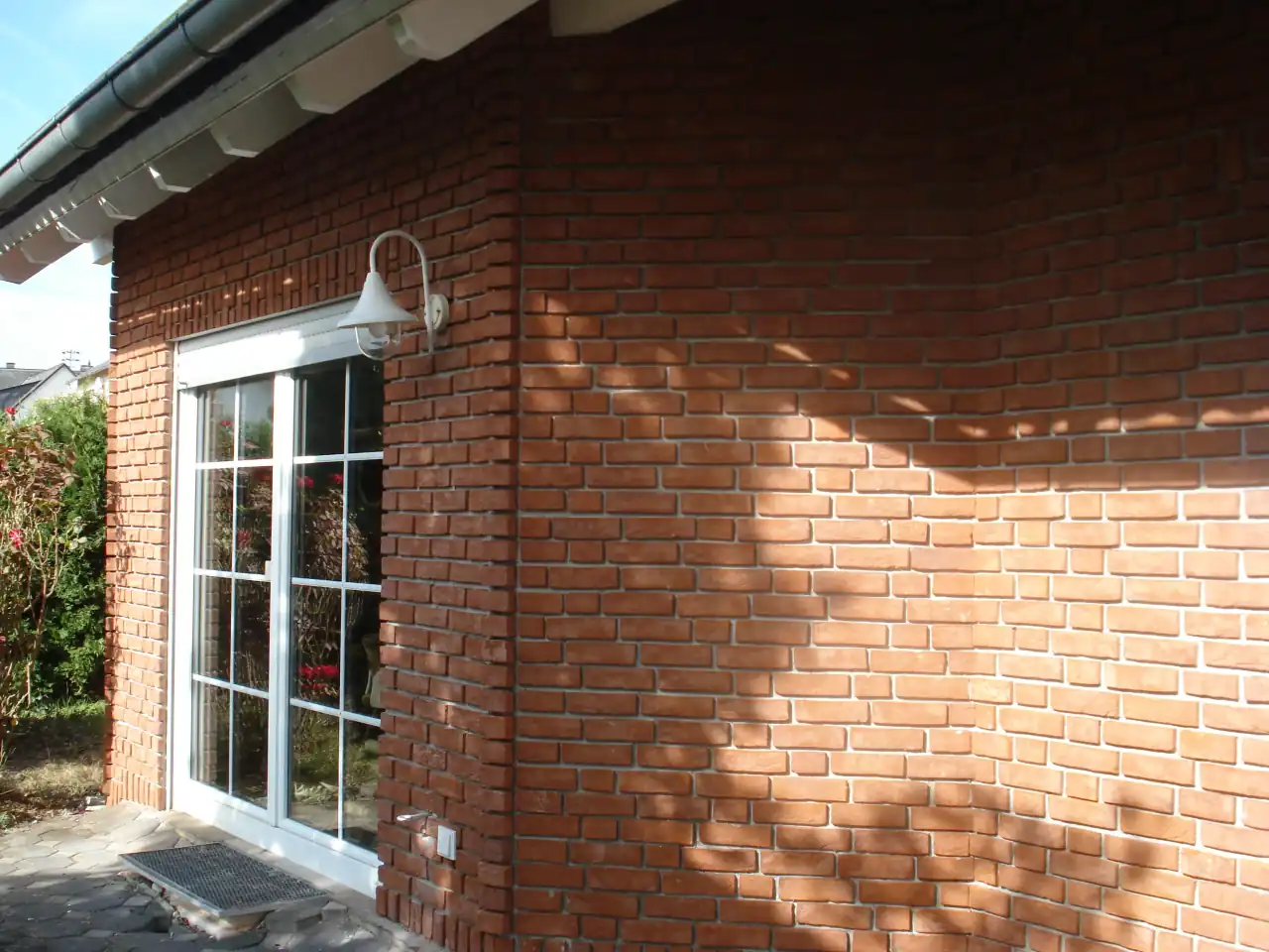 Terrasse eines Einfamilienhauses mit weißen Fenstern und roter Klinkerfassade