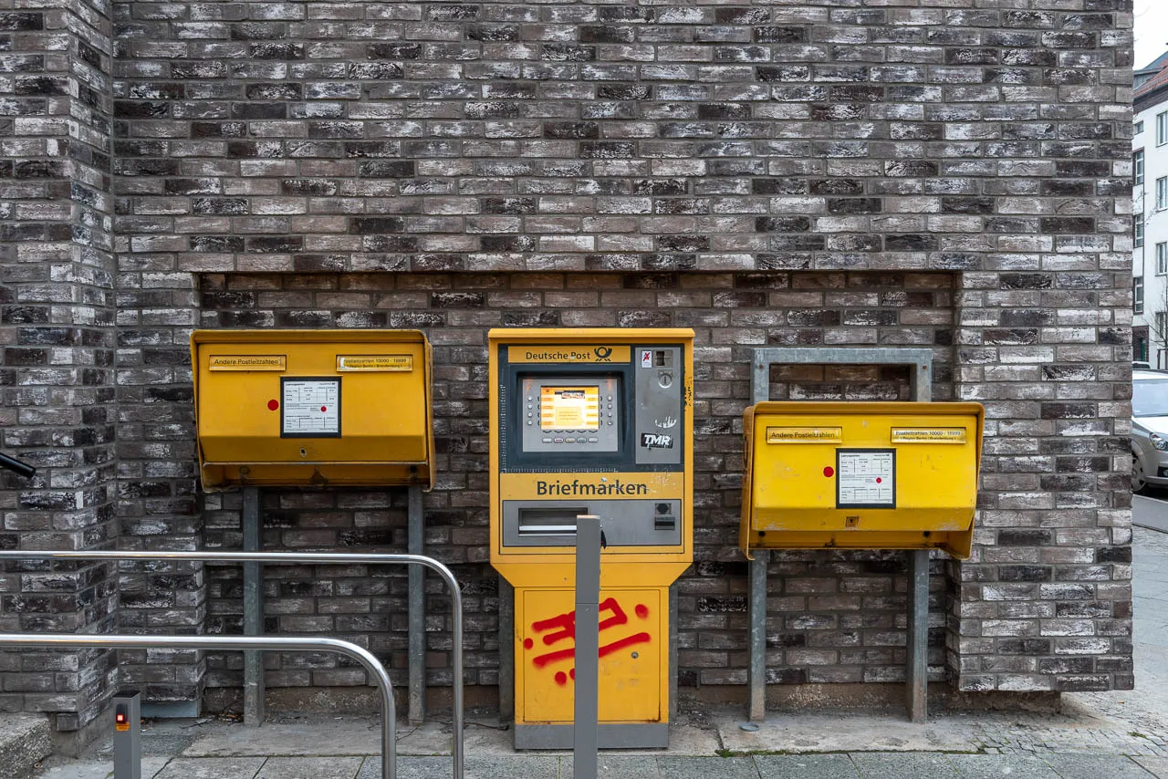 DHL Postkästen vor einer schönen Klinkeraußenfassade. Die Sorte Retro Shadow mit schwarzen und grauen Backsteinriemchen - ein dunkler, moderner Anblick
