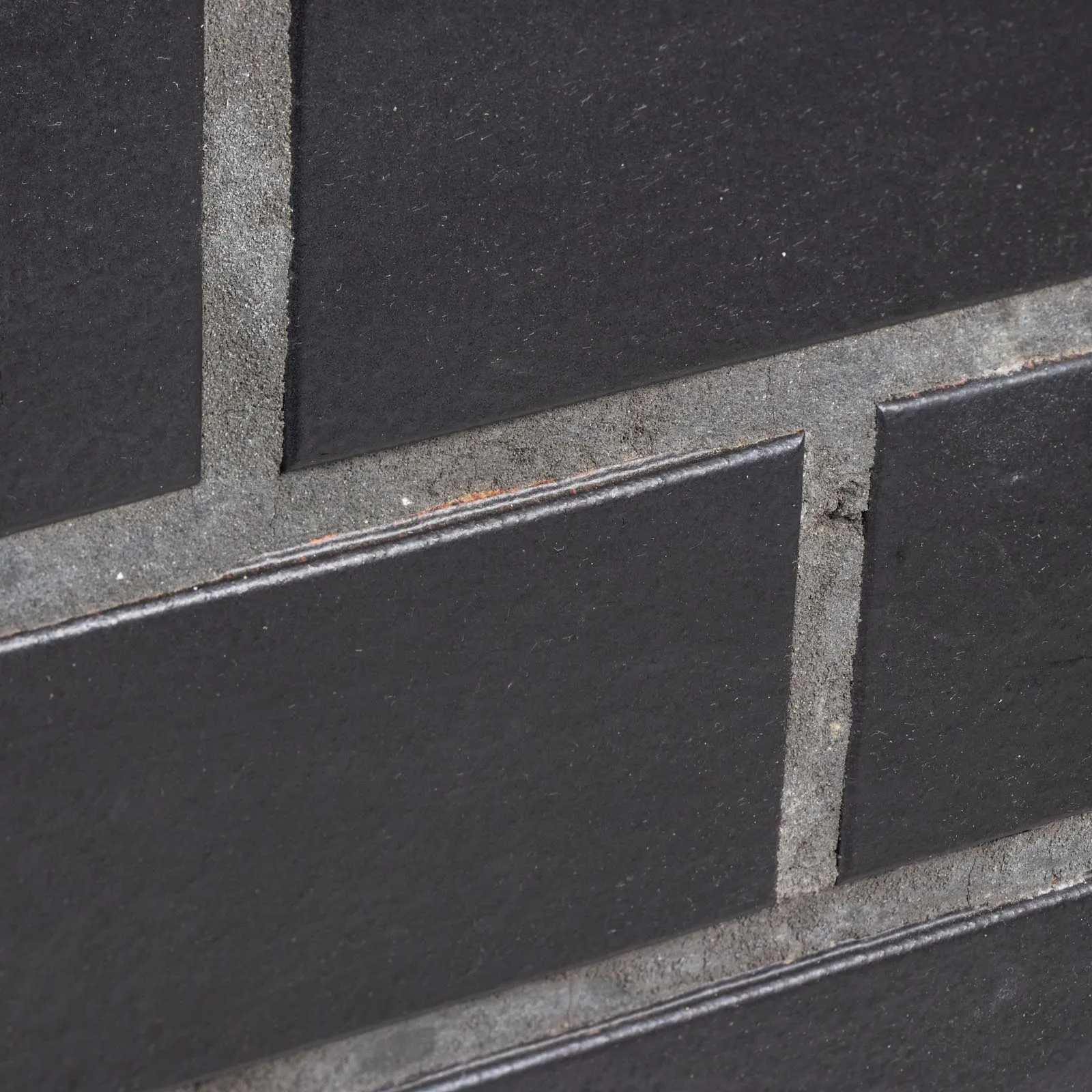 Produktbild schräg  im Detail Spaltriemchen Panther schwarz glatt. Klinkerriemchen mit glatter schwarzer Oberfläche. Auf dem Bild in grau / anthrazit verfugt.