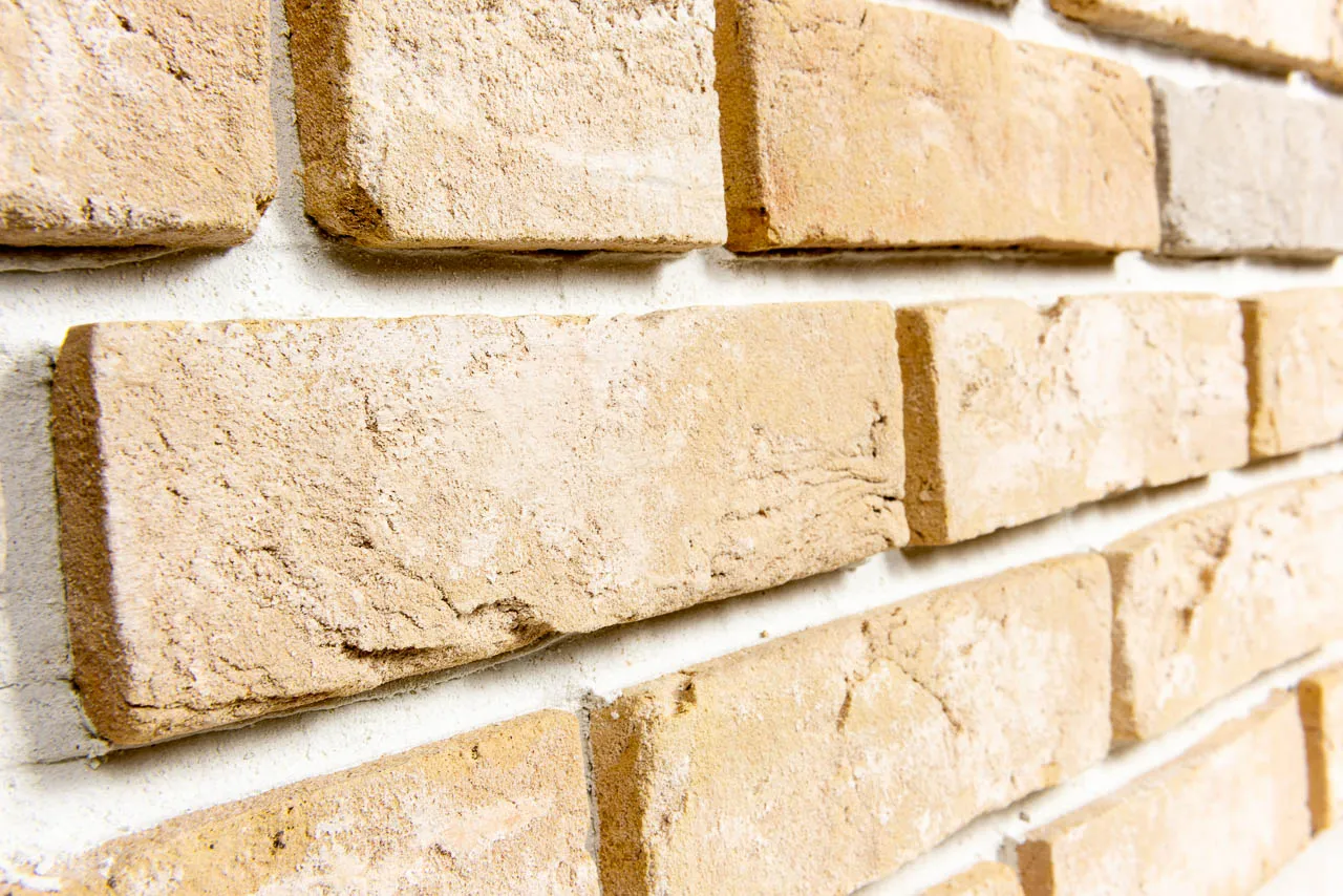 Backsteinriemchen Antik gelb Antik gelb Produktbild schräg. Gelbes Riemchen mit Kalk geschlämmt und vereinzelt mit grau, grünen Steinen sortiert.