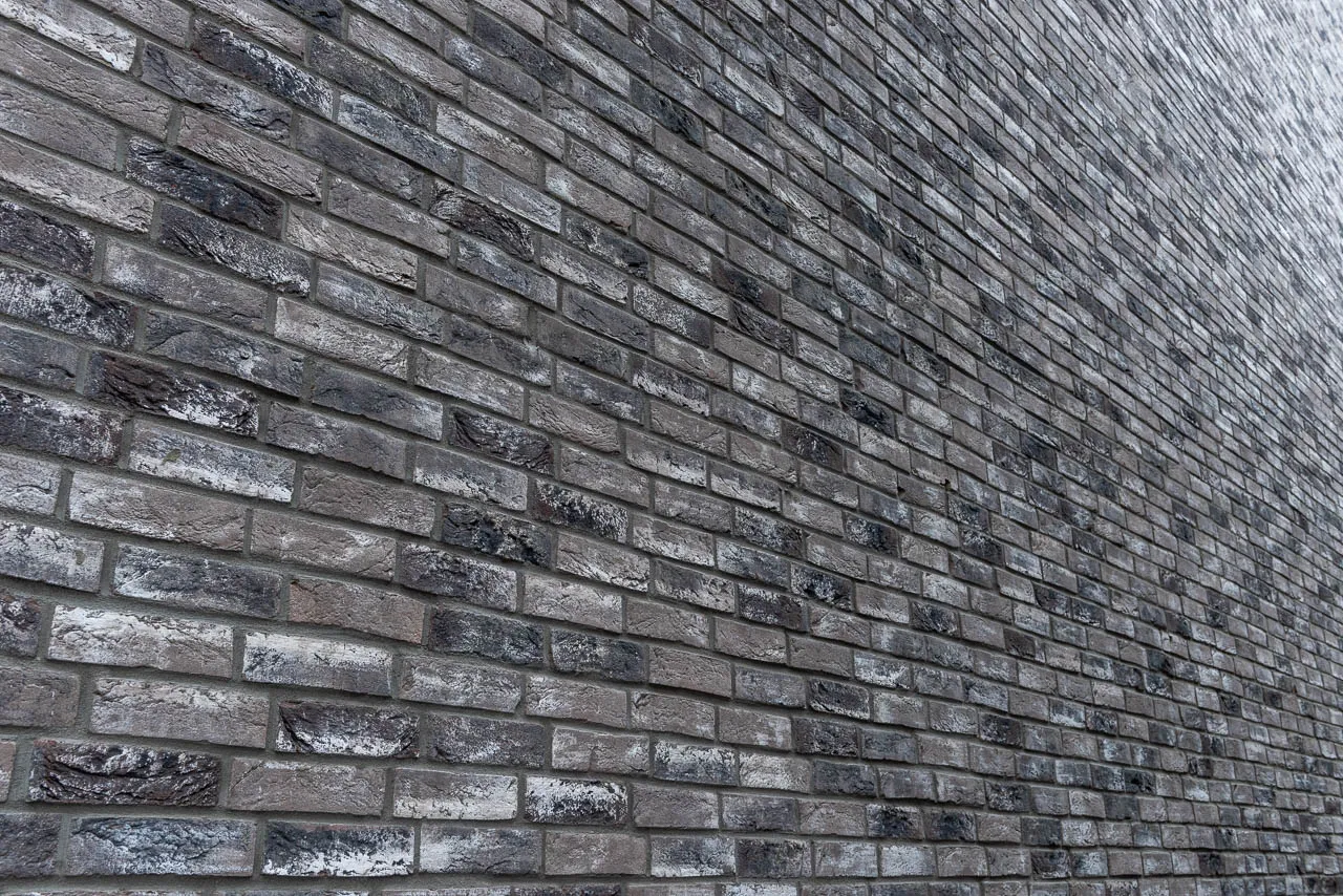 Backsteinwand aus Retro Shadow Klinkerriemchen. Die schwarzen und grauen Steine mit der weißen Schlämme wirken dunkel und dennoch stilsicher und modern. Über eine große Fläche ergibt sich ein tolles Bild