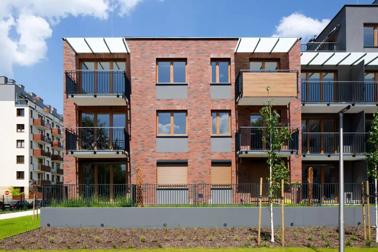 Frontansicht eines Wohnhauses mit Balkonen und roter Hauswand