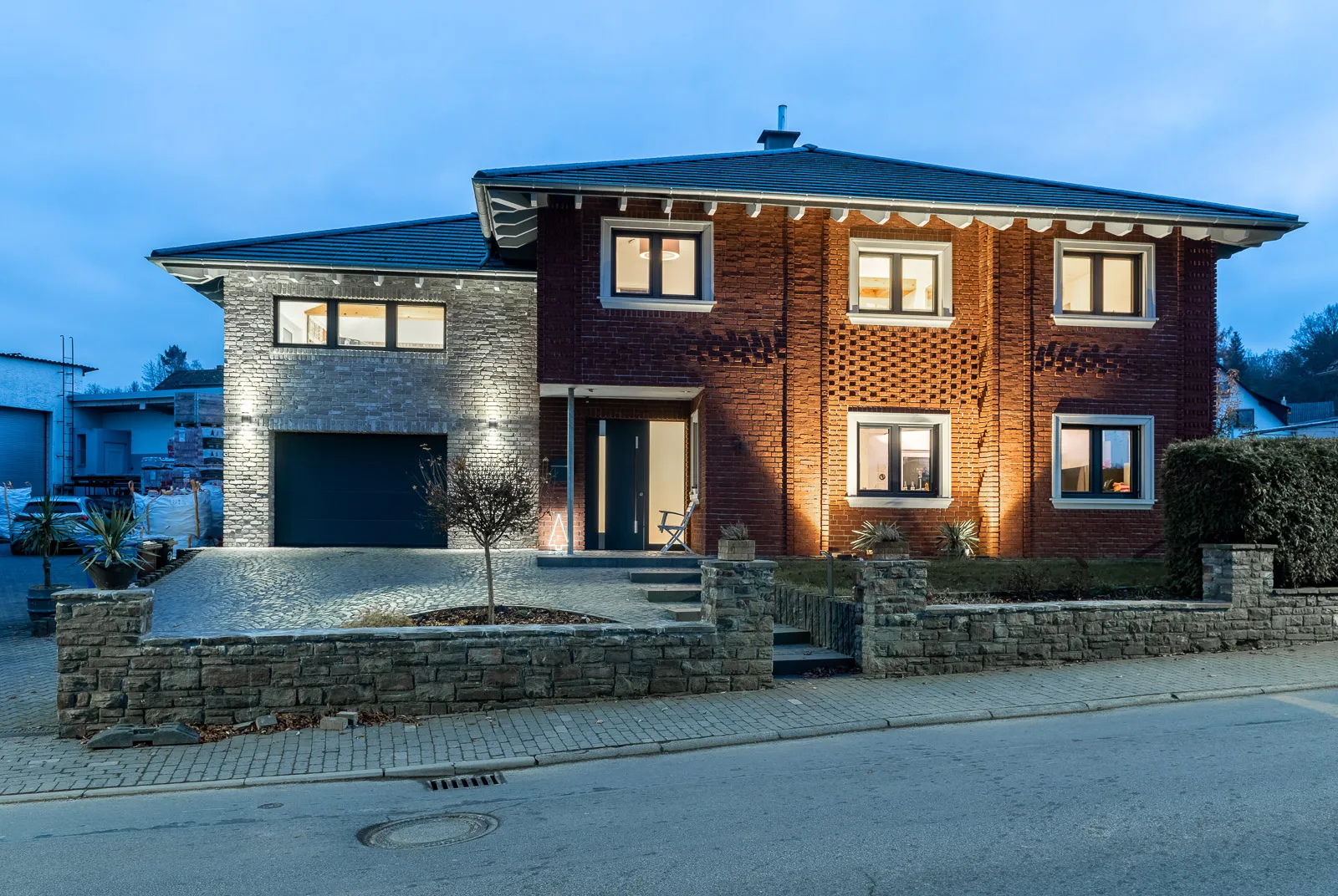 Klassisches rotes Klinkerhaus. Eine ganze Hausfassade mit den kraftvollen Riemchen der Sorte Rotgeflammt. Mit der Beleuchtung am Abend wirkt das Haus harmonihsc, gemütlich und einladend