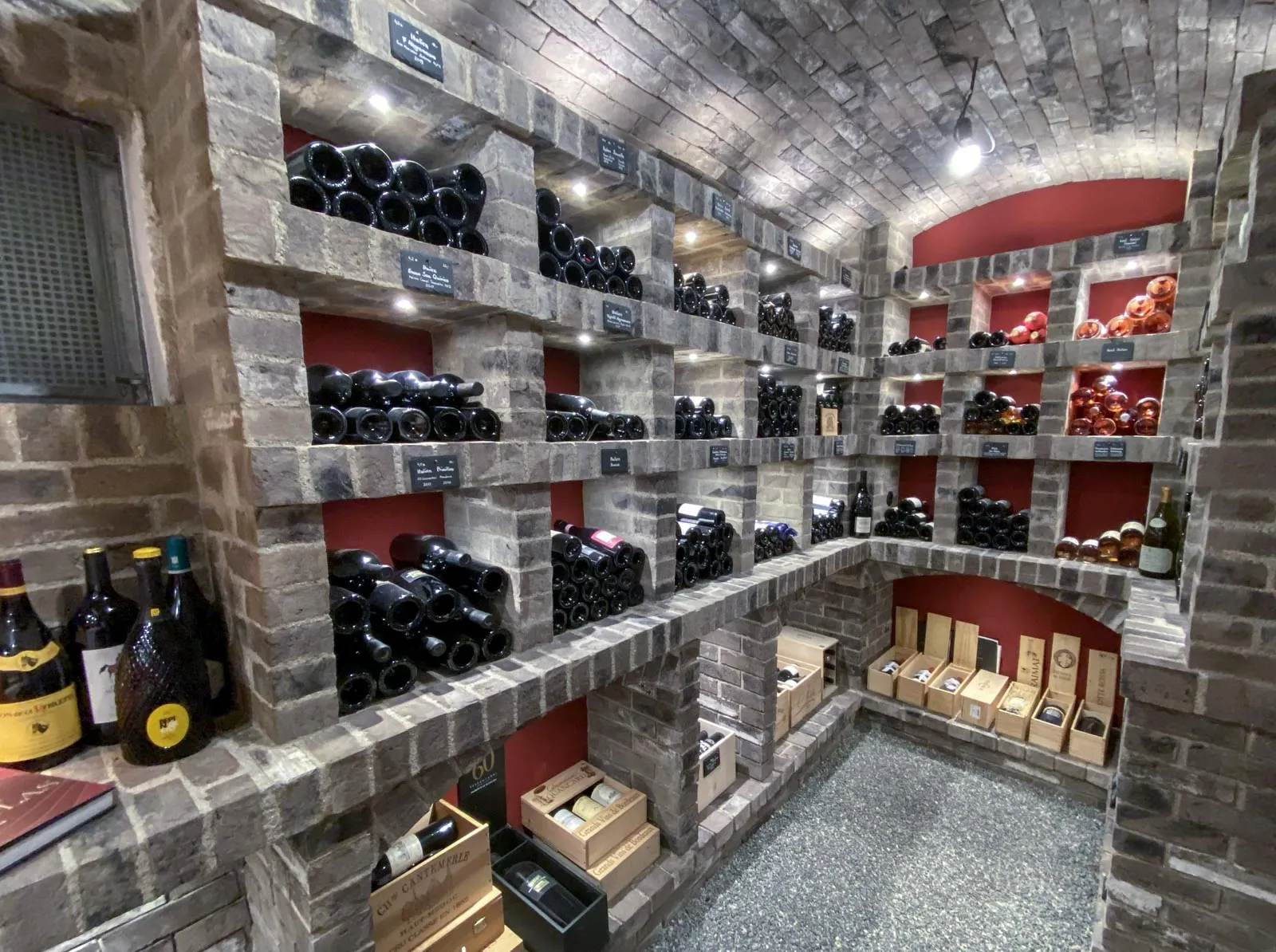 Cooler, beeindruclender Weinkeller. Von den Wänden über die gewölbte Decke bis zu den Weinfächern ist hier alles mit den dunkelgrauen Riemchen verlegt worden. Entstanden ist ein echtes Kellergewölbe