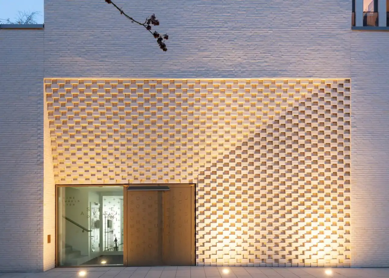 Eingangsbereich mit großer Holztür und Außenfassade mit gelb-weißen Riemchen