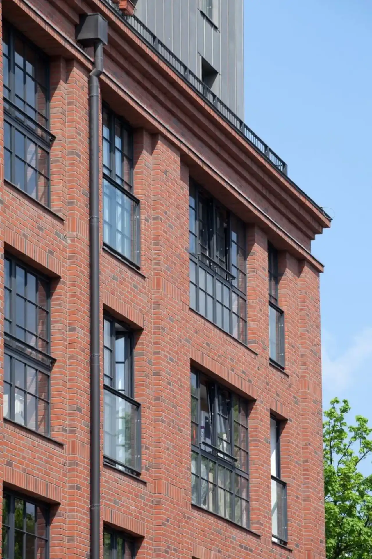 Mehrfamilienhaus mit dunklen Fenstern und roter Aussenfassade