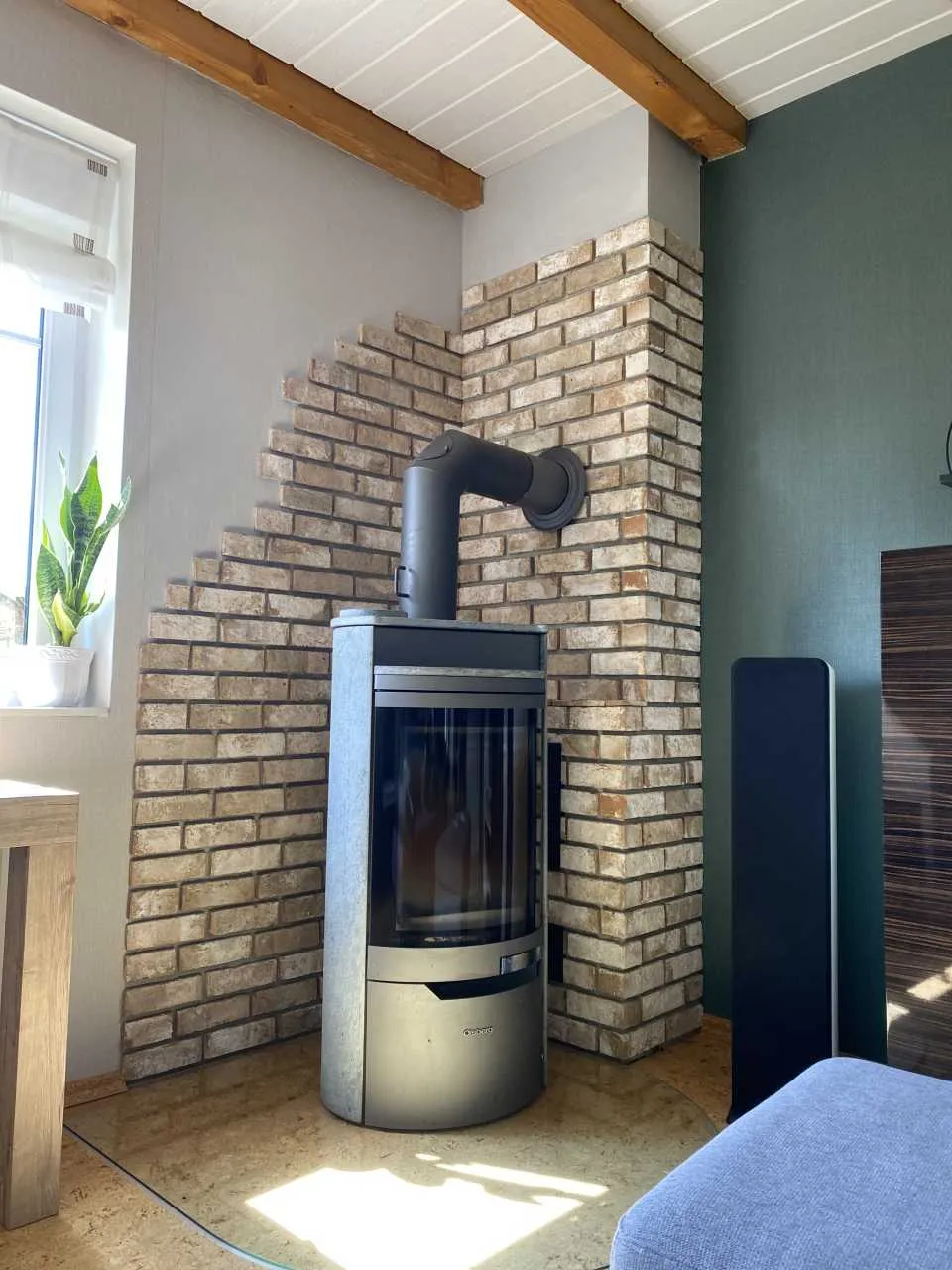 Schöne, helle Kaminrückwand, die über zwei Wände verlegt wurde und an einer Wand ausläuft. Die helle Wand aus gelb, bronznen Riemchen mit leichtem Rotstich passt super zum Holzboden und zur Holzdecke