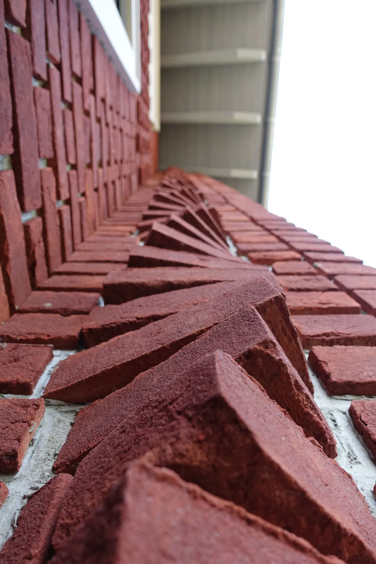 Tolle Detailaufnahme von rotgeflammter Klinkerriemchen und Steinen, die versetzt als Wirbel an der Hausfassade verarbeitet wurden. Dies gibt das gewisse Etwas im Gesamtbild