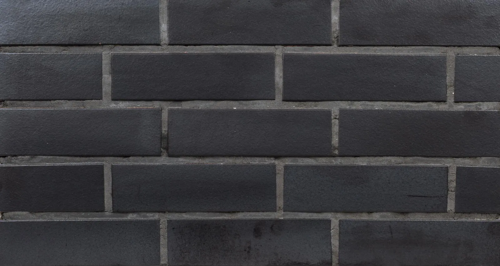 Produktbild frontal Spaltriemchen Panther schwarz glatt. Klinkerriemchen mit glatter schwarzer Oberfläche. Auf dem Bild in grau / anthrazit verfugt.