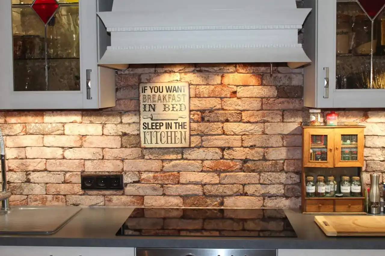 Schöne Küchenrückwand, die fugenlos mit Antik classic rot braun verlegt wurde. Passt perfekt zur weißen Küchenfront und wirkt durch Beleuchtung gleich modern und einladend.