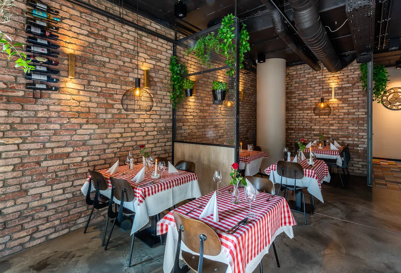Backsteinwand im gemütlichen Restaurant.Die roten Klinkerriemchen mit teilweise gelben und schwarzen Brand wirken mit Beleuchtung noch einladender. Ein schönes Gesamtbild uas klinker und holz