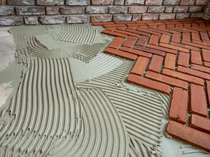 Rote Riemchen die gerade in ein frischgezahntes Klebebett gelegt werden