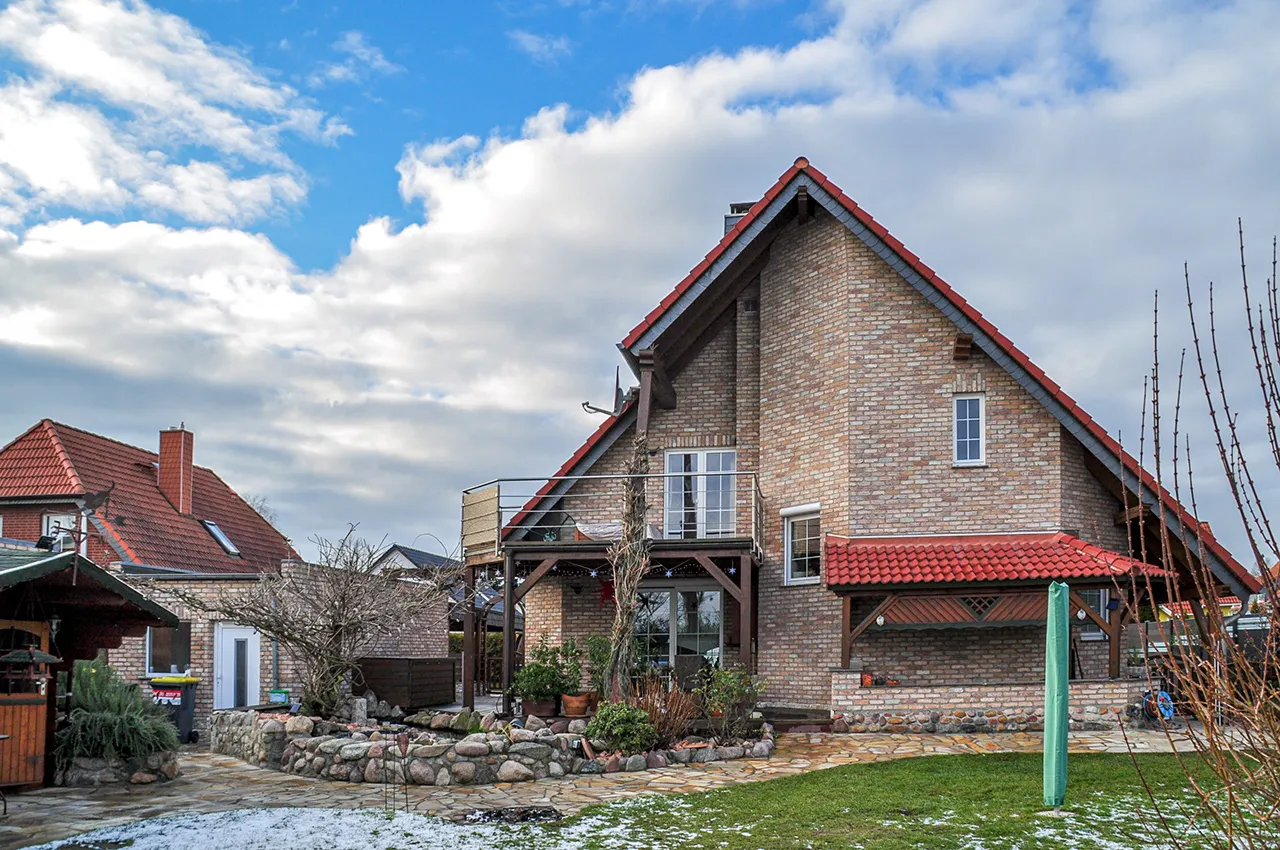 Haus mit Backsteinriemchen Mediterran Finca und orangener Ueberdachung