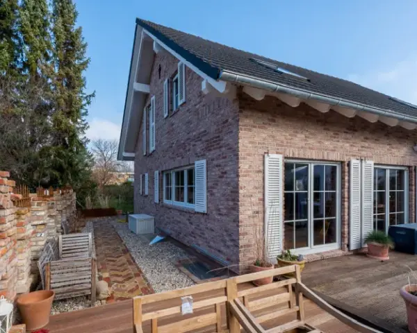 Haus verklinkert mit dem Klinkerriemchen Antik edel, weißen Klappläden und einer Gartenmauer aus Klinkern