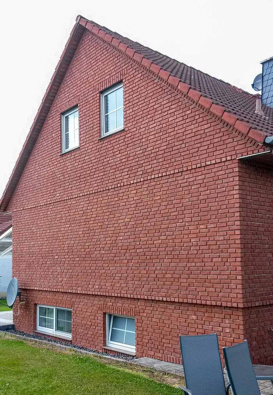 Klassisch rote Außenfassade mit weißen Fenstern. Die Sorte Rubinrot wirkt hier im freundlichen, einladenden Rotton ganz klassisch und zeitlos