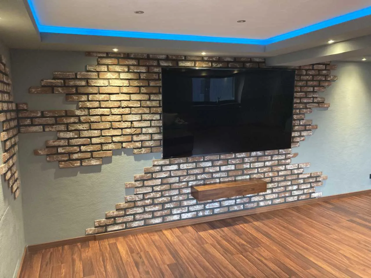 backsteinwand die quer beet als tv-rückwand verlegt wurde. die klinkerriemchen der sorte antik rustik in rot-bunt wirken hier durch die graue verfugung etwas dunkler und leicht bräunlich